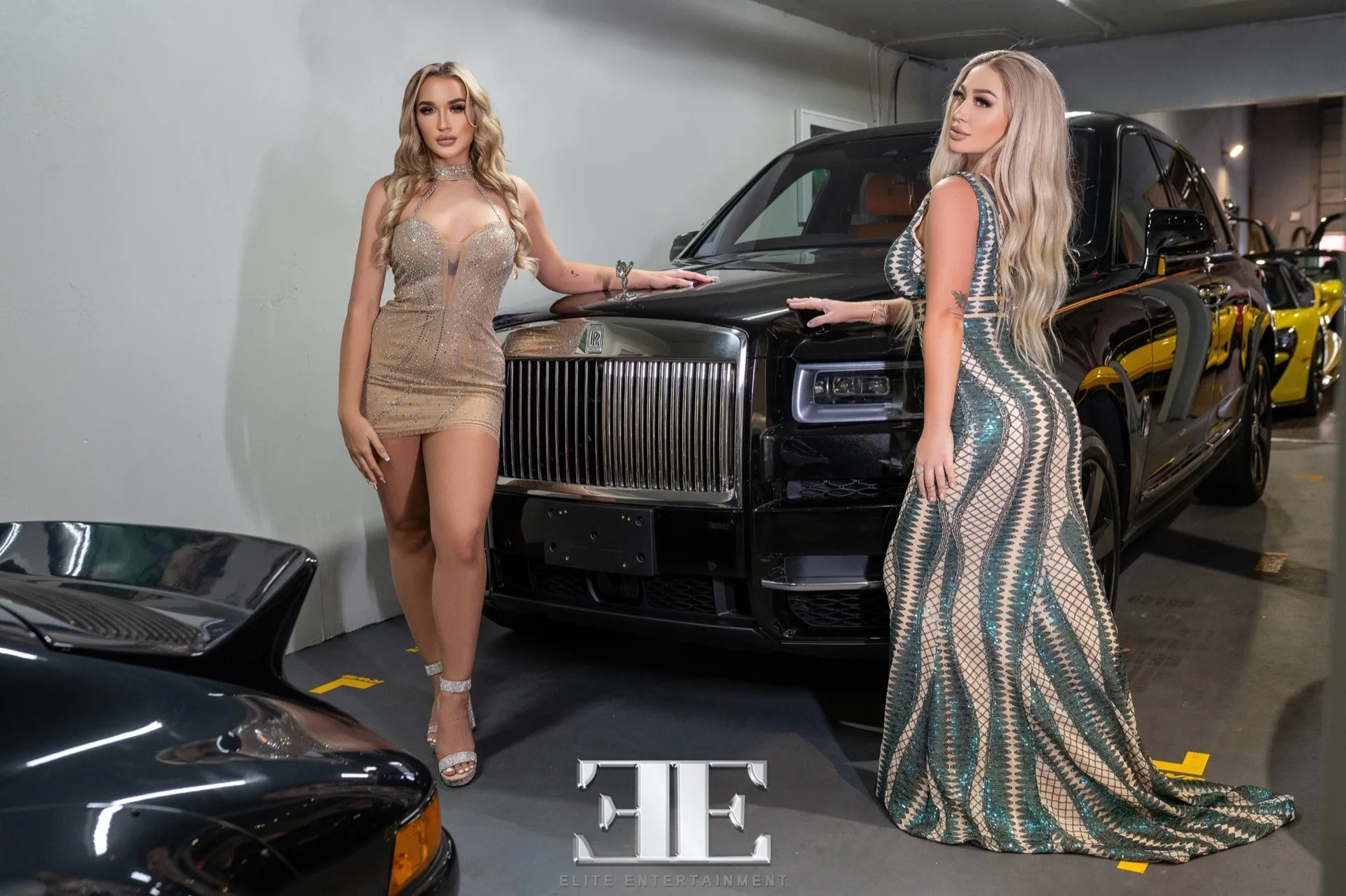 Two Elite Entertainment models beside a luxury vehicle